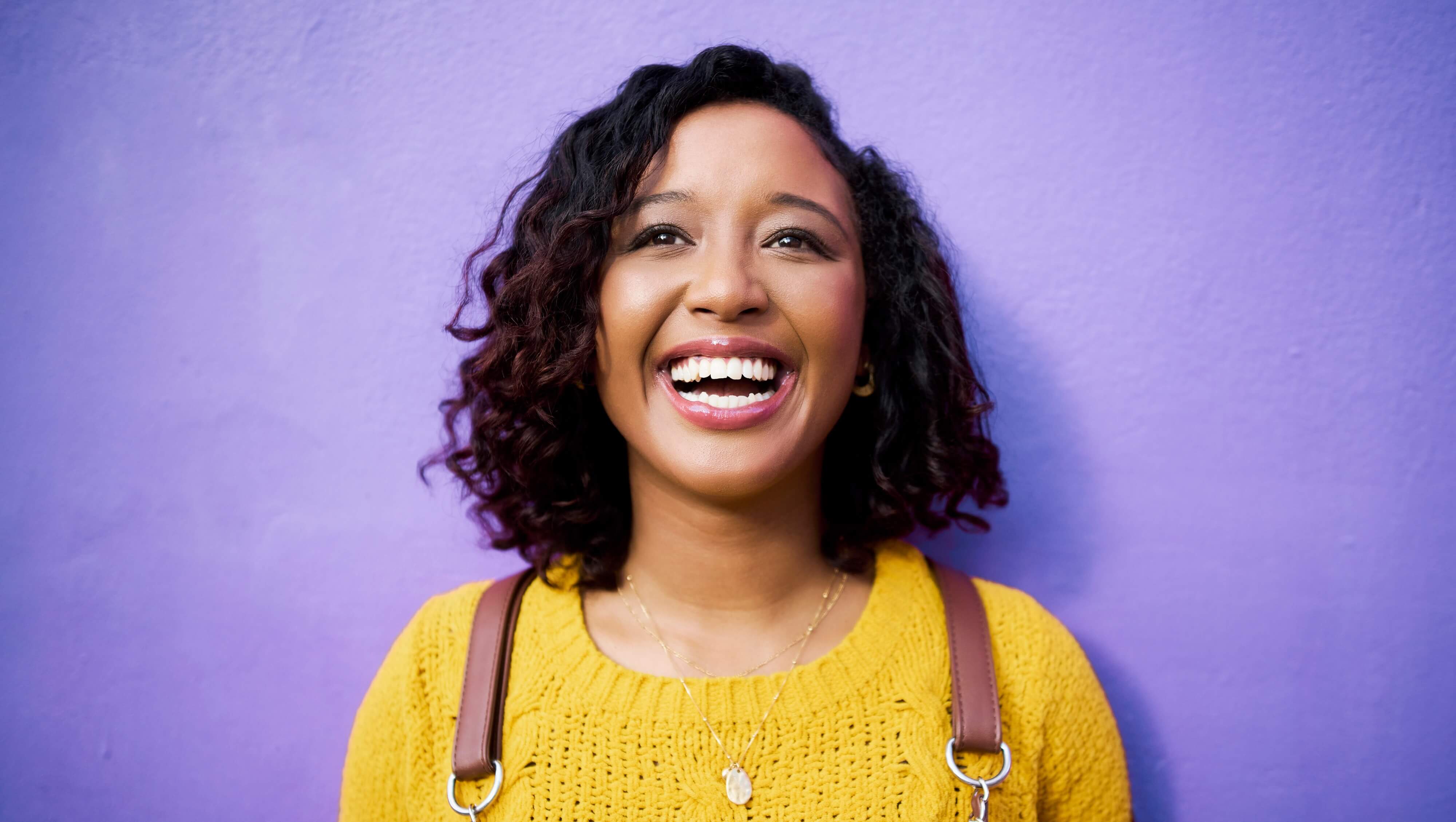 Mulher sorrindo na frente de fundo roxo