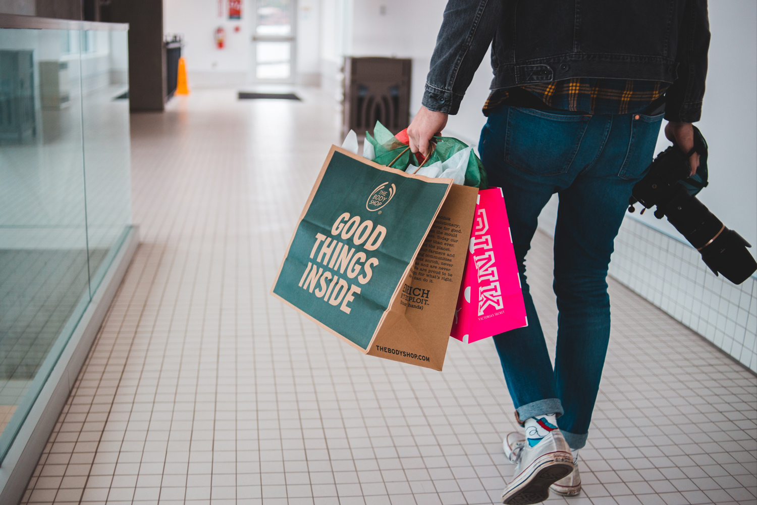 A man carrying shopping bags in a mall.