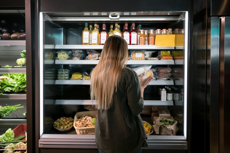 Woman choosing food from supermarket fridge